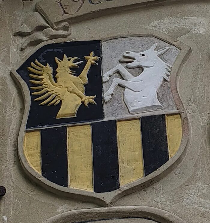 Wappenschild der Familie Eben von Racknitz: halb gespalten und geteilt mit goldenem Greifen, silbernem Esel und drei schwarzen Pfählen in Gold